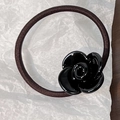 Detailed macro shot of a black resin rose charm on a coffee-colored elastic hair tie - Black