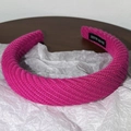 Gros plan du bandeau tricoté rose avec étiquette tissée noire Hand Made - Rose rouge