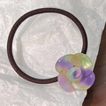 Detailed close-up of a brown elastic hair tie with a colorful resin floral ornament - Purple Green Mix