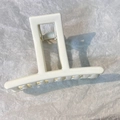 Close-up of a cream-colored rectangular hair claw clip with a glossy finish and metal spring - Cream Rectangle