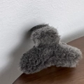 Primer plano de una pequeña pinza de pelo de felpa gris con textura de piel sintética - Gris