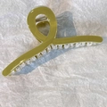 Dettaglio della grande pinza per capelli verde oliva e trasparente con molla in metallo - verde senape
