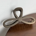 Close-up of matte brown butterfly hair claw clip for long hair on wooden table - Coffee