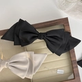 Detailed macro view of black and beige multi-layered satin bow hair clips with spring fasteners - Black