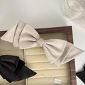 Detailed macro view of large layered cream bow hair clip in a wooden jewelry box - Apricot