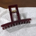 Close-up of translucent burgundy rectangular hair claw clip with golden metal spring - Coffee