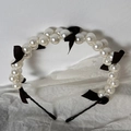 Detail of elegant headband featuring double-row faux pearls and black ribbon bows - Black