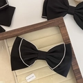 Dettaglio macro di un fermaglio per capelli a fiocco nero con strass su vassoio - Fiocco Inclinato