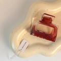 Dettaglio di un fermaglio per capelli rettangolare in resina ambrata su vassoio beige - Borgogna