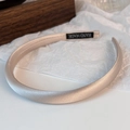 Primer plano detallado de diadema de satén champán con etiqueta artesanal sobre la tela - Albaricoque Nude