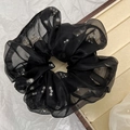 Detailopname van zwarte mesh scrunchie met grijze parels op een houten sieraden tray - Zwart