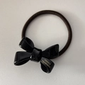 Detailed macro view of black acrylic bow hair tie with golden FRANCE Handmade text - Black