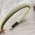 Detailed macro of mint green fabric headband with handmade tag and fine stitching - Light Green
