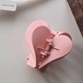 Detailed macro view of the matte pink heart-shaped hair claw clip with its metal spring - Pink