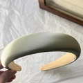 Dettaglio di un cerchietto in raso verde chiaro che mostra la consistenza imbottita - verde chiaro