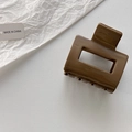 Detailed close-up of a hollow rectangular dark brown resin hair claw clip on a white surface - Caramel color
