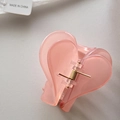 Detail view of the pink heart-shaped hair claw with its golden metal spring and resin texture - Jelly Pink