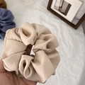 Close-up of a large champagne silk scrunchie with soft satin folds and elegant texture - Apricot
