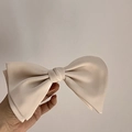 Detailansicht einer großen cremefarbenen Satin-Doppelschleife mit seidiger Textur - Aprikose