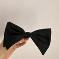Detail of a large double-layered black satin bow hair clip held by hand with elegant texture - Black