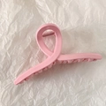 Dettaglio della molletta per capelli rosa con molla su carta bianca testurizzata - Croce