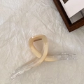 Macro di una grande clip per capelli beige e trasparente su carta bianca ruvida - Cachi