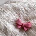Gros plan détaillé d'une barrette noeud rose doux sur un fond en tissu texturé - Nœud Rose Vif