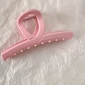 Detailed top view of large pink matte hair claw clip on textured white fabric background - Cross Straight Line