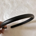 Close-up of black leather textured skinny headband held against a white background - Black