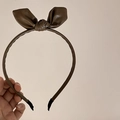 Detailed view of brown PU leather headband with bow knot and lychee grain texture - Coffee