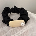 Close-up of black pleated hair scrunchie with resin detail and an elegant pearl inlay - Beige