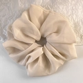 Makroansicht des beigen Oversize-Haargummis aus Chiffon mit weichen Stofffalten - Aprikose