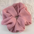 Detail eines rosa Chiffon-Haargummis mit eleganten Falten und feiner Textur im Detail - Rosa