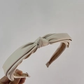 Close-up of beige fabric knotted headband with matte satin texture and brown lining - Apricot