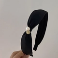 Dettaglio del cerchietto nero annodato con perla bianca e ciondolo dorato inciso - Stile Largo / Nero
