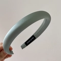 Detailed macro view of green satin sponge headband with handmade brand label detail - Green