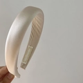 Detail view of champagne satin padded headband with smooth silk texture and soft cushioning - Apricot