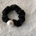Detail of black pleated fabric scrunchie featuring a large white pearl with golden metal base - Flat Pearl Style