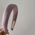 Close-up of a wide padded satin headband in dusty pink with soft silky sheen texture - Pink