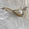 Détail d'une pince à cheveux dorée en forme de sirène avec strass scintillants et perle - Sirène Strass