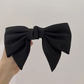 Close-up of a large black fabric bow hair clip featuring elegant layered matte texture - Black