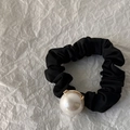 Détail d'une grande perle blanche sur un chouchou en satin noir plissé avec base dorée - Perle de 2cm avec Support