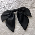 Macro detail of large black satin bow hair clip with soft matte silk texture - Black