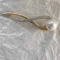 Dettaglio di elegante fermaglio per capelli dorato con strass lucidi e una perla grande - Perla + Strass