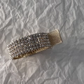 Dettaglio della molletta dorata con strass e trama a rete antiscivolo su sfondo bianco - Strass Oro