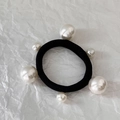 Dettaglio macro di un elastico nero per capelli ornato con sei eleganti perle bianche - Combinazione di Tre Perle Grandi E Tre Piccole