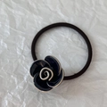 Detailopname van een blauwe camellia haarelastiek met getextureerd zwart weefsel - Marineblauw