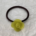 Dettaglio di un elastico marrone ad alta elasticità con un fiore di camelia verde lucido - Verde