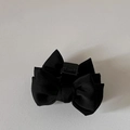 Detailed top view of the layered black matte fabric bow hair claw clip on a white surface - Black