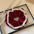 Detailopname van een fluwelen haarelastiekje met kanten randen op een dienblad - Rood fluweel